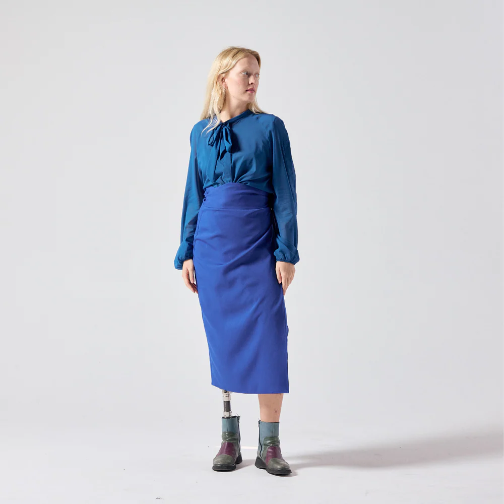 Woman with lower limb prosthetic wears long electric blue pencil skirt